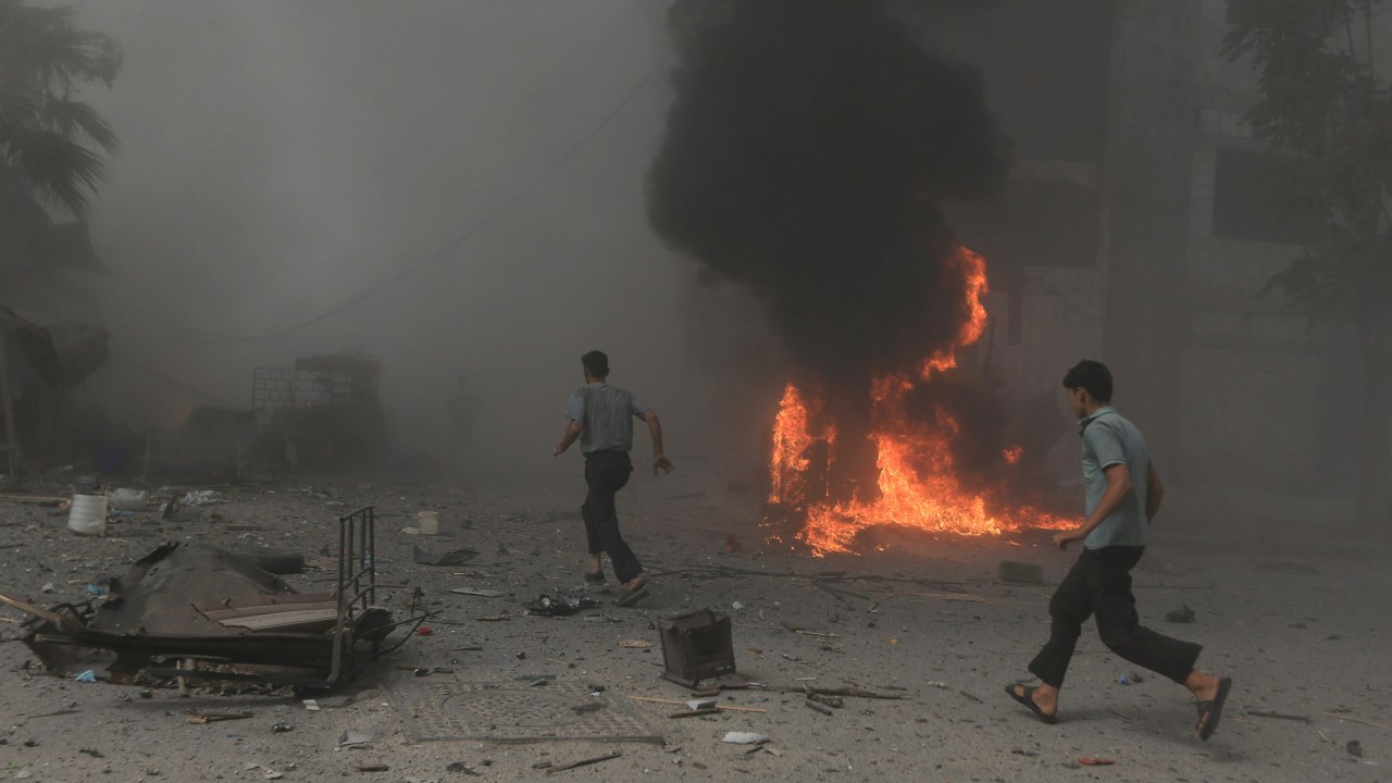 Homens correm em marcado atingido por bombardeio de aliados do governo de Bashar al-Assad, em Damasco, Síria