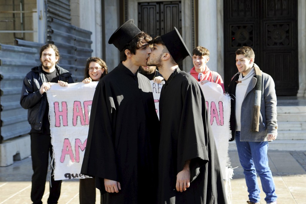 Ativistas dos direitos homossexuais se beijam durante um protesto contra a homofobia em frente à Catedral de Atenas