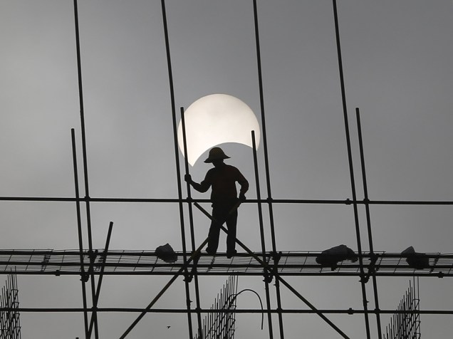 <p>Eclipse solar é visto por trabalhador de construção, no Camboja</p>