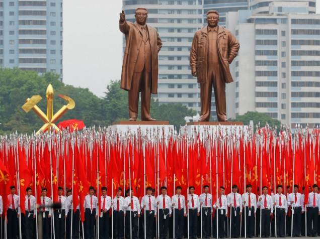 Estudante seguram bandeiras em frente a estátuas de Kim Il Sung e Kim Jong Il, ex-ditadores da Coreia do Norte, no desfile que celebra o último dia do congresso do Partido dos Trabalhadores