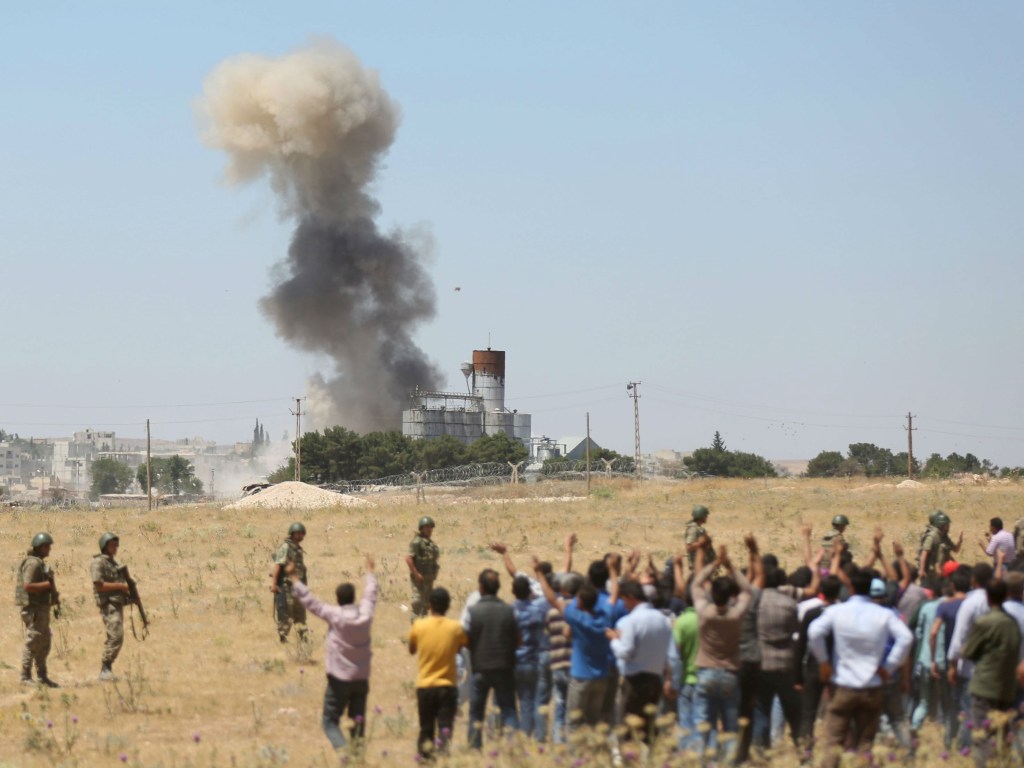 Refugiados sírios observam fumaça decorrente de ataque dos terroristas do Estado Islâmico contra a cidade de Kobani