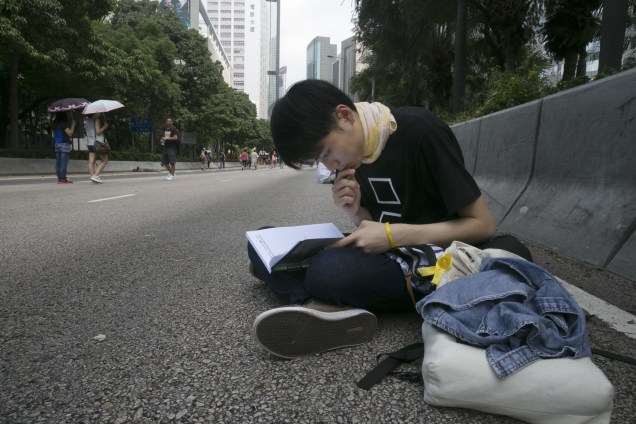 Em uma rua de Hong Kong, estudante aproveita calmaria em meio a protestos para fazer a lição de casa