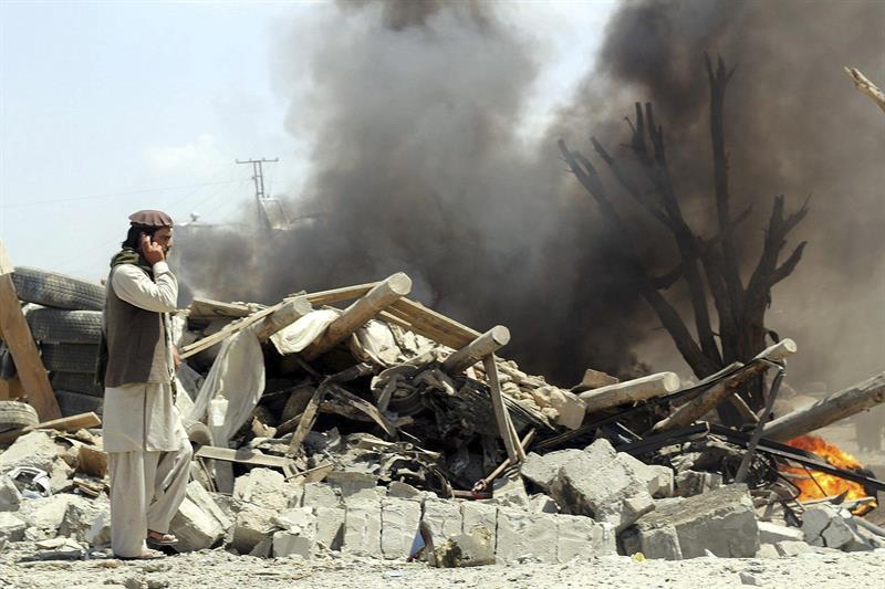 Afegão fala ao telefone próximo aos destroços do mercado atacado