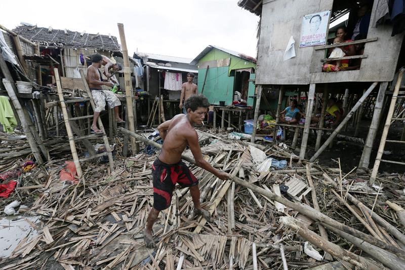 Morador de área atingida recolhe destroços após passagem do tufão Rammasun pelas Filipinas