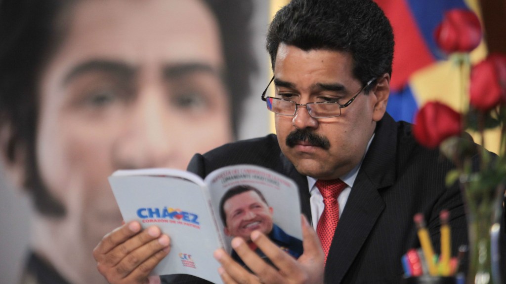 O presidente venezuelano Nicolás Maduro lê um livro sobre Hugo Chávez em seu gabinete oficial