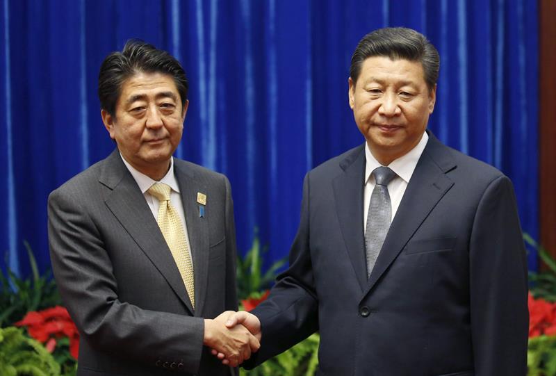 O primeiro-ministro japonês (dir.) Shinzo Abe ao lado do presidente chinês Xi Jinping