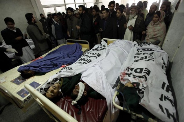 Pessoas observam vítimas do ataque contra uma escola no Paquistão