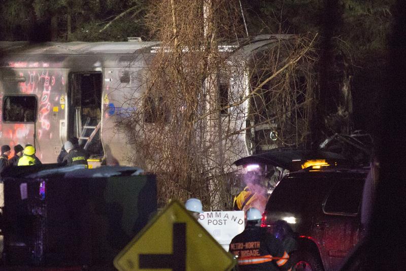 Bombeiros observam o vagão destruído após o trem se colidir com um carro, em num subúrbio de Nova York