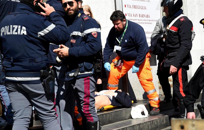 Policiais e equipes de socorro auxiliam um ferido em frente ao Palácio da Justiça de Milão