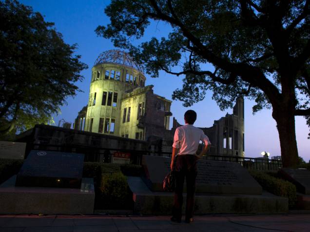 Homem olha o Domo da Bomba Atômica ao anoitecer em Hiroshima, Japão. O Domo conhecido no japão como "Genbaku Dome", é a única estrutura que continuou em pé neste distrito da cidade, e foi preservado como uma memorial da paz