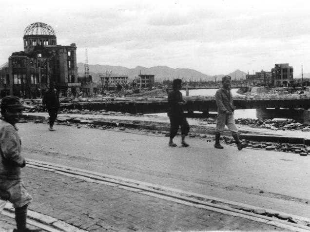 Moradores passam em frente ao Palácio das Indústrias de Hiroshima, hoje conhecido como Domo da Bomba Atômica, na ponte Aioi, após o ataque contra Hiroshima no dia 6 de agosto de 1945