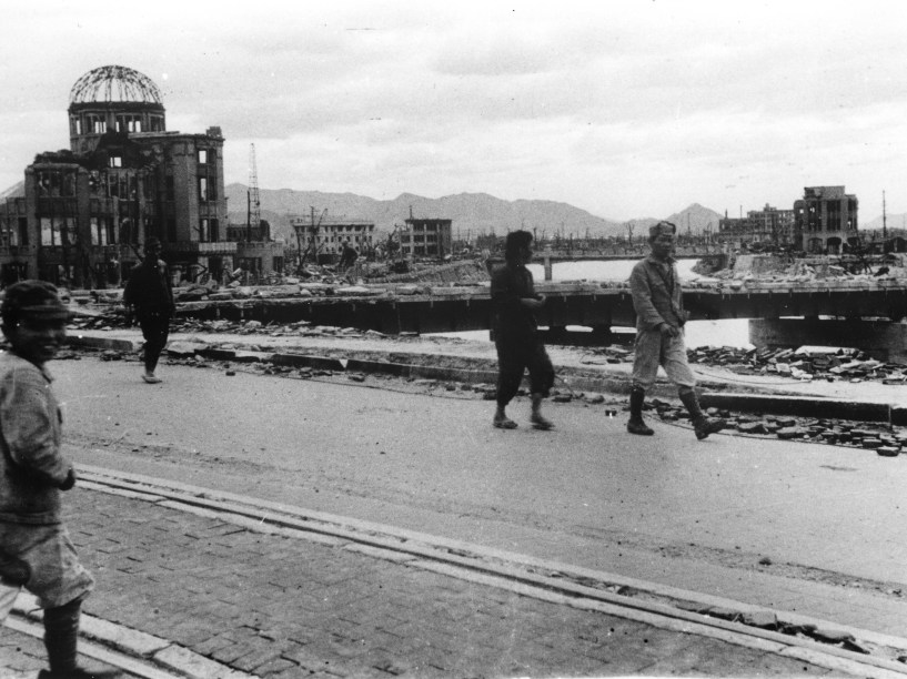 Moradores passam em frente ao Palácio das Indústrias de Hiroshima, hoje conhecido como Domo da Bomba Atômica, na ponte Aioi, após o ataque contra Hiroshima no dia 6 de agosto de 1945