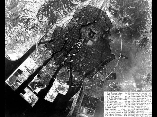 Imagem mostra o impacto da bomba na cidade de Hiroshima. O epicentro da explosão está marcado por um pequeno círculo branco, enquanto a área de devastação pode ser vista pela superfície negra que marca a cidade. O ataque a Hiroshima foi seguido três dias depois por um ataque a Nagasaki