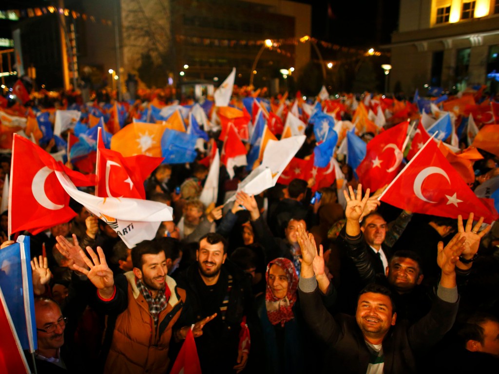 Pessoas acenam bandeiras em frente à sede do Partido AK, em Ancara, na Turquia