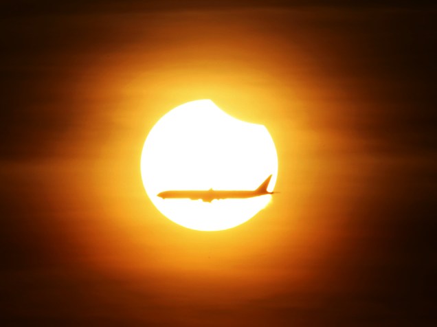 <p>Avião comercial passa enquanto acontece o eclipse solar parcial em Cingapura, nesta quarta-feira (09)</p>