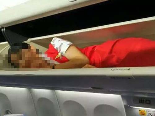 Aeromoça dentro do compartimento superior de bagagens de avião da Kunming Airlines
