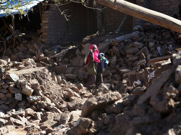 Mulher paquistanesa caminha entre escombros de casas destruídas após terremoto
