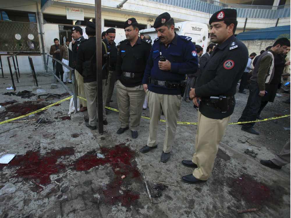 Policiais inspecionam o local do atentado, em Mardan, no Paquistão