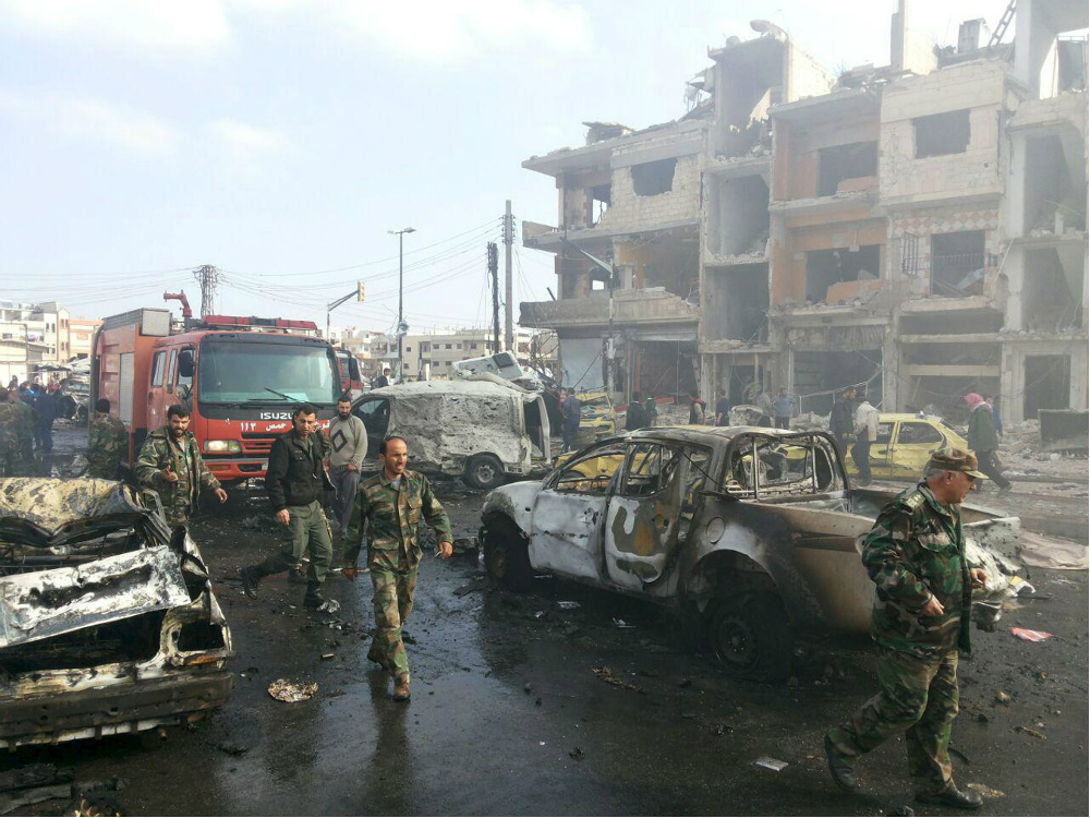 Militares do Exército sírio vistoriam os carros-bombas que explodiram em Homs