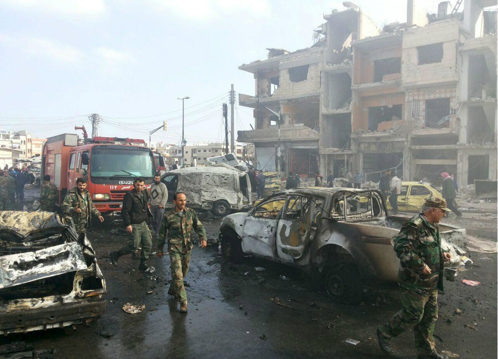 Militares do Exército sírio vistoriam os carros-bombas que explodiram em Homs