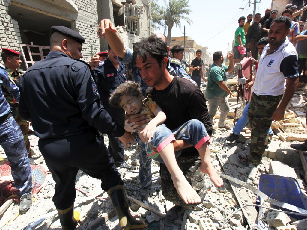Homem carrega um menino que foi achado debaixo de destroços após bombardeio em Bagdá