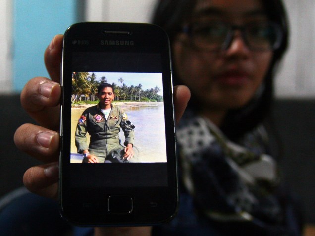 Parente de uma das vítimas segura um smartphone com a foto do Capitão da Força Aérea da Indonésia, Sandy Permana, um dos tripulantes do avião militar C-130 Hercules, que caiu em uma área residencial na cidade de Medan, na Indonésia