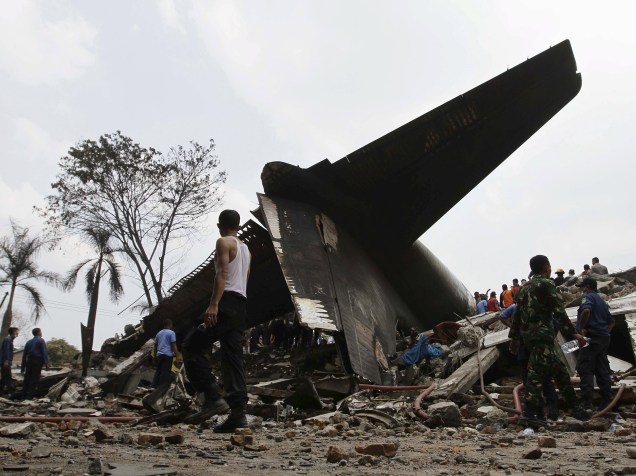 Equipe de resgate examina os destroços do avião militar C-130 Hercules, após queda em uma área residencial na cidade de Medan, na Indonésia. O avião de transporte colidiu dois minutos após a decolagem, a cinco quilômetros de distância da base