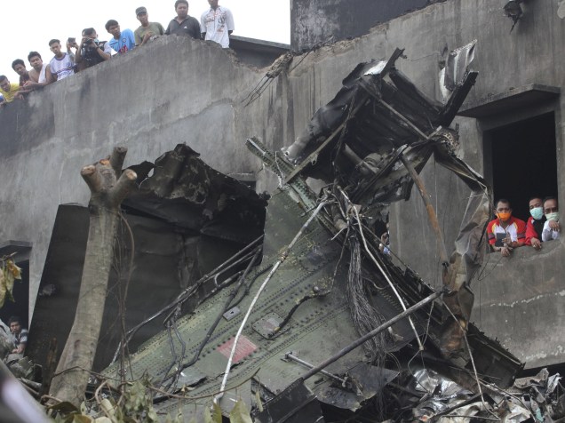 Pessoas observam os destroços do avião militar C-130 Hercules, após queda em uma área residencial na cidade de Medan, na Indonésia