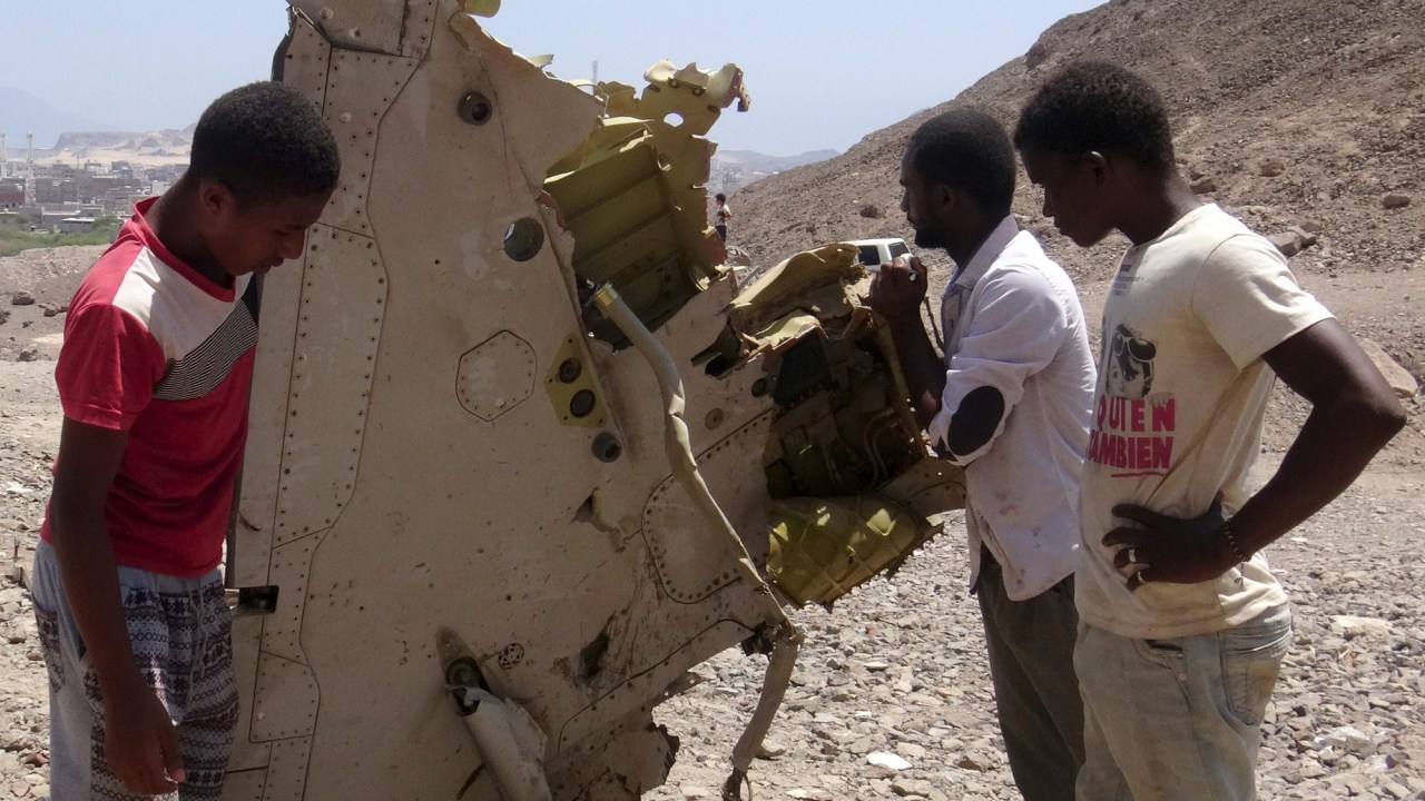 Garotos observam destroços de avião dos Emirados Árabes que caiu no Iêmen, matando os dois pilotos, nesta segunda-feira (14)