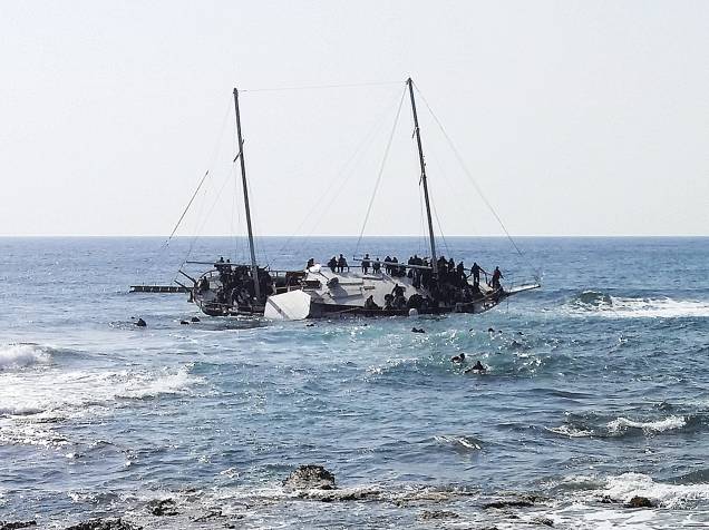 Imigrantes que tentavam chegar a Grécia, são vistos na água tentanto alcançar a costa da ilha de Rodes