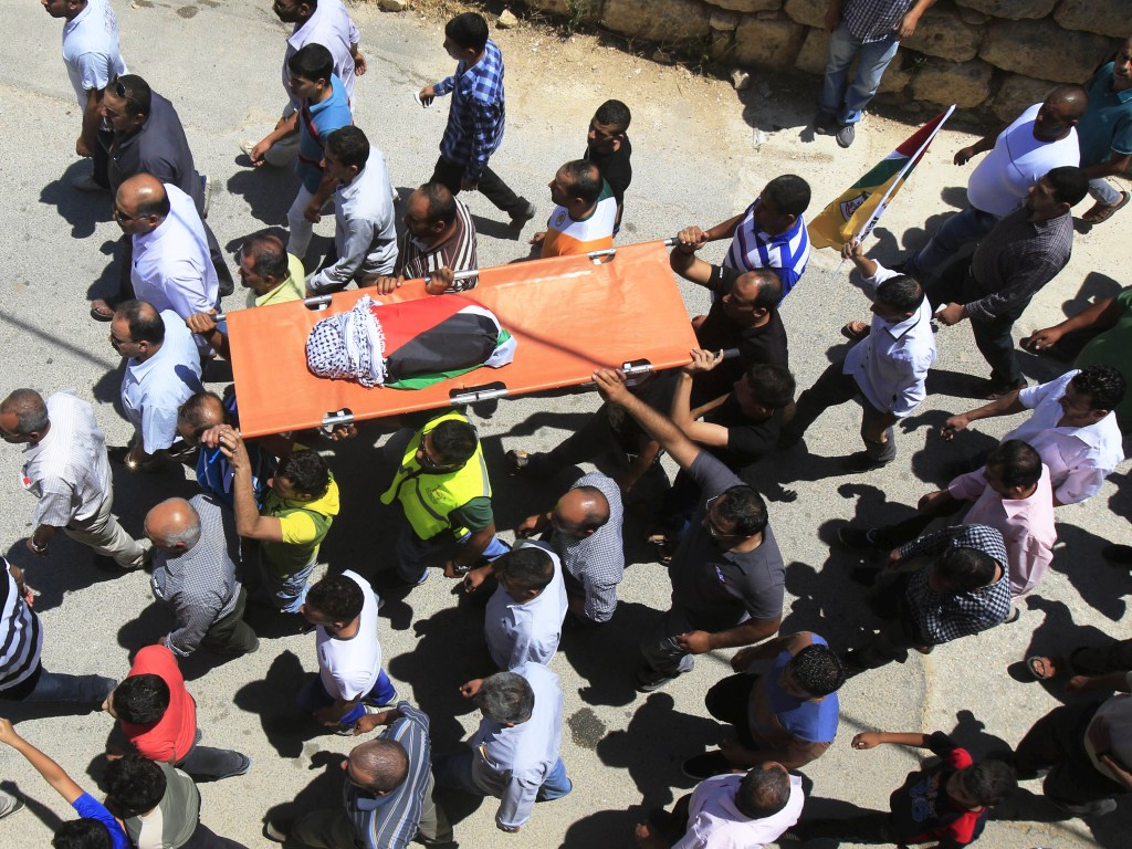 Palestinos carregam o corpo de um bebê que morreu durante incêndio em sua casa em Duma, na Cisjordânia