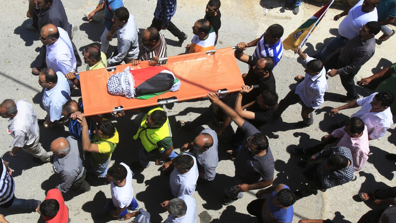 Palestinos carregam o corpo de um bebê que morreu durante incêndio em sua casa em Duma, na Cisjordânia