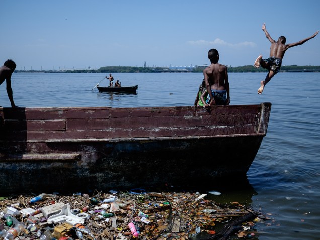 <p>Menino salta de um barco na água poluída da Baía de Guanabara, no Rio de Janeiro - 18/01/2015</p>