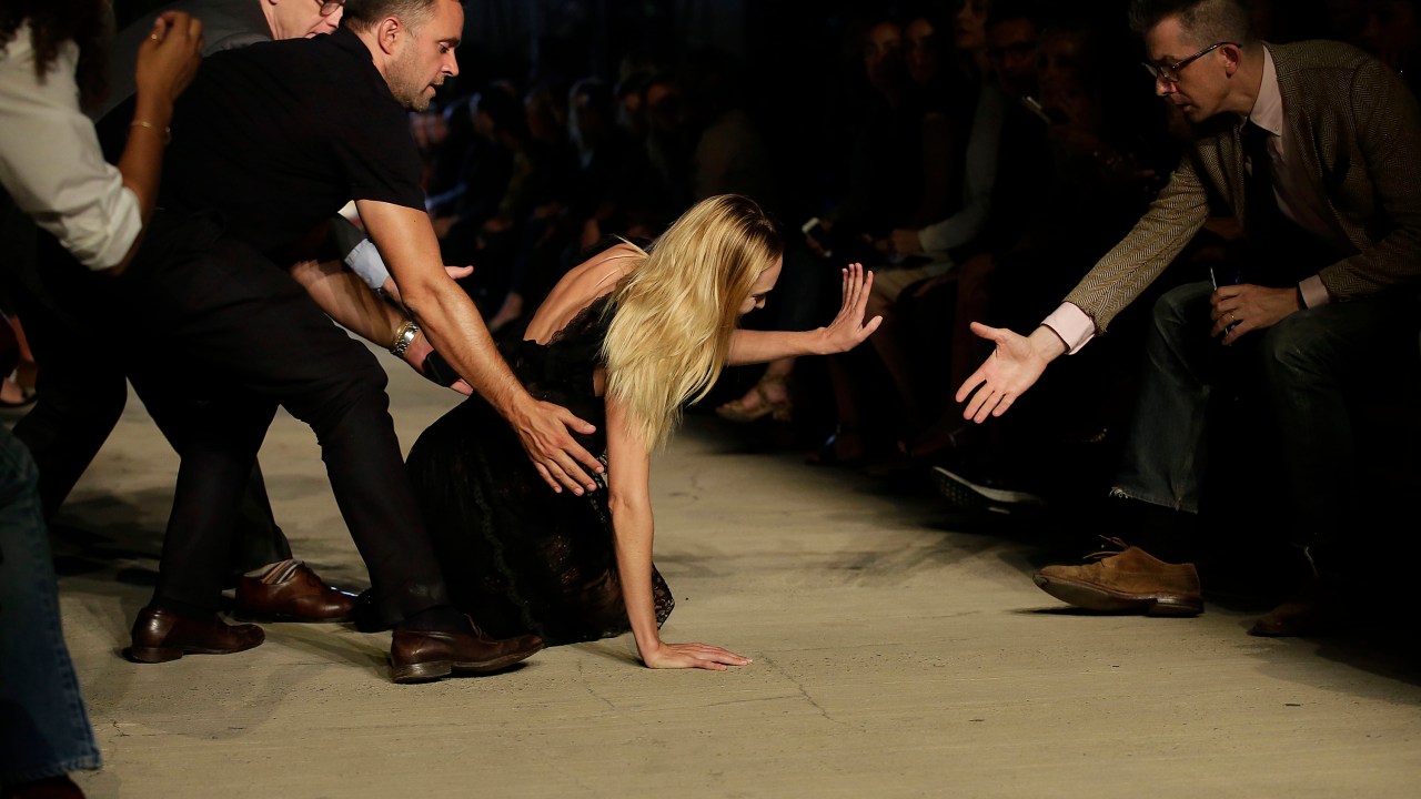 A modelo Candice Swanepoel recebe auxílio após cair durante desfile da Givenchy, em Nova York