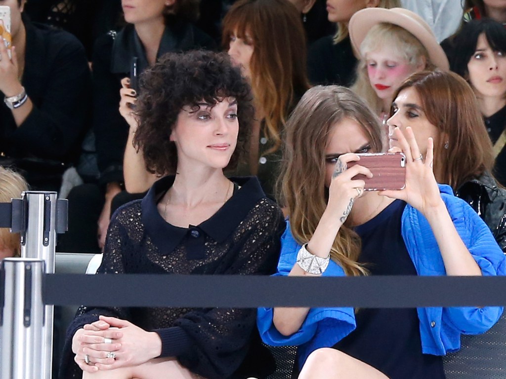 A cantora 'St. Vincent' e a modelo Cara Delevingne são vistas usando o mesmo anel no dedo anelar durante a Paris Fashion Week