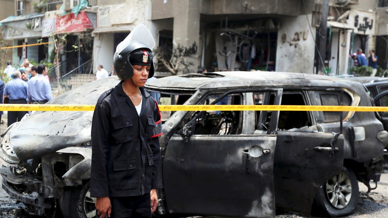 Policial observa o local onde um carro-bomba explodiu, matando o procurador-geral do Egito, Hisham Barakat
