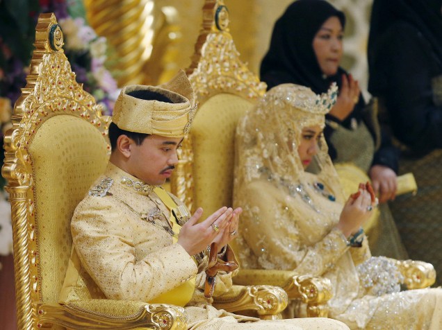 Os recém casados rezam durante a cerimônia no Palácio Istana Nurul Iman, considerado o maior palácio residencial do mundo