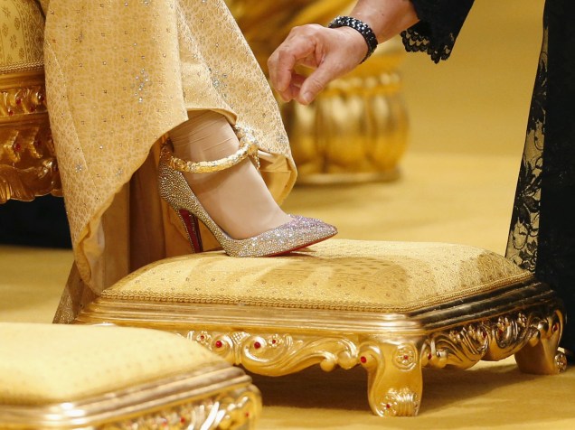 Mulher ajusta o vestido e os sapatos Christian Louboutin, cravejados em cristais Swarovski, da noiva, enquanto aguarda a chegada do príncipe
