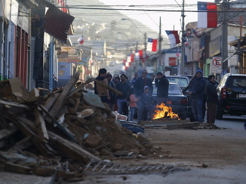 Pessoas recolhem destroços depois do terremoto que atingiu a zona central do Chile
