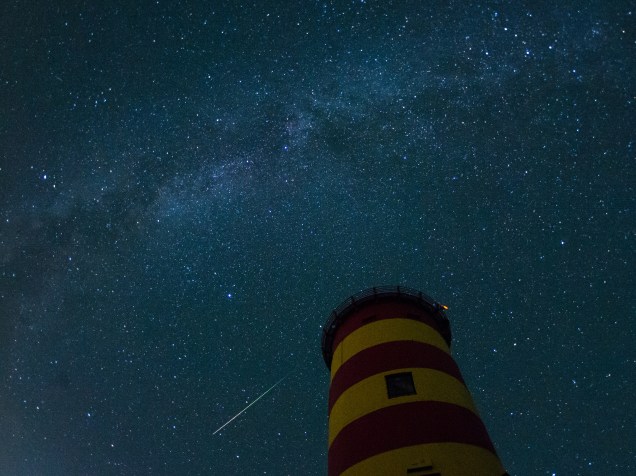 <p>Uma estrela cadente cruza o céu atrás do farol em Pilsum, noroeste da Alemanha, durante o pico da atividade da chuva anual de meteoros Perseidas - 13/08/2015</p>