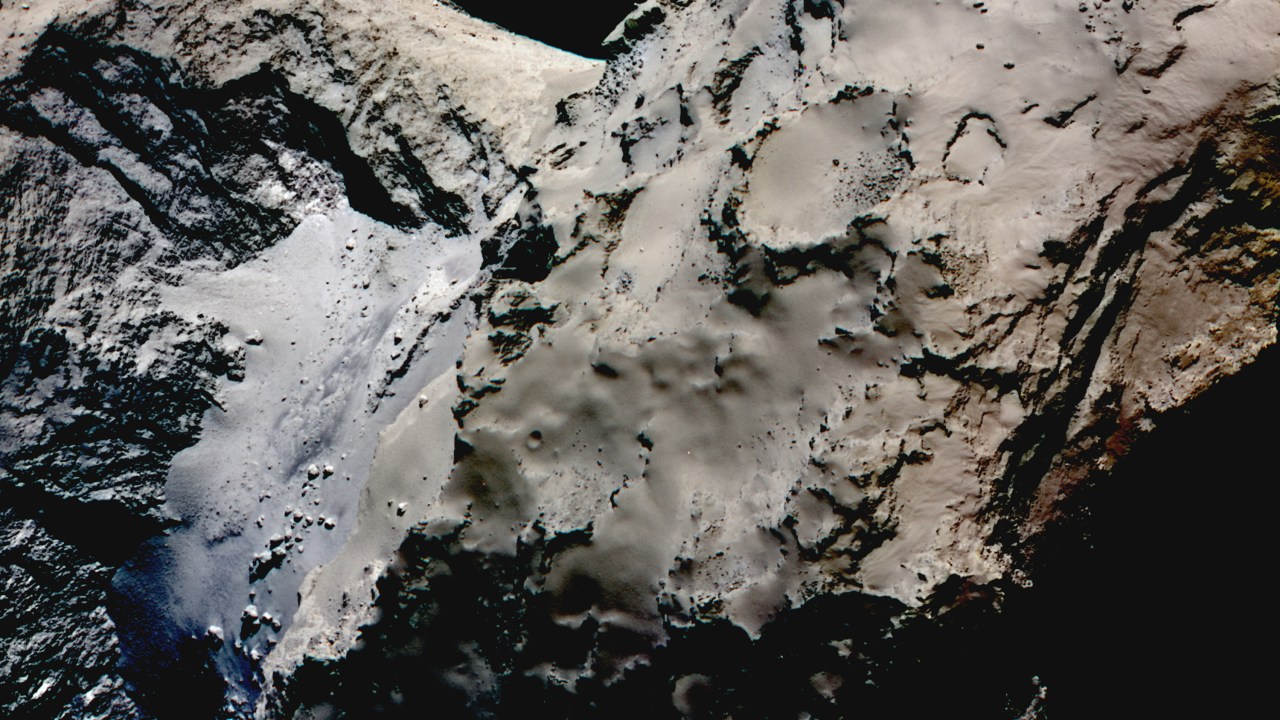 Diferença de coloração entre a região do 'pescoço' (mais azulada) e o resto do cometa. Nesta imagem, as cores foram reforçadas para ressaltar a diferença