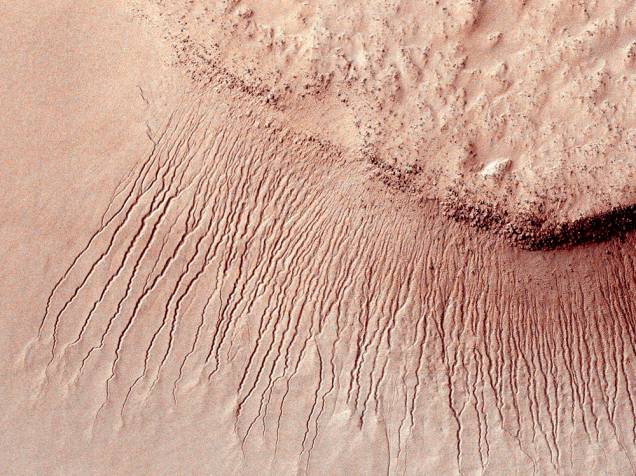<p>Superfície marciana fotografada pela missão Mars Reconnaissance Orbiter (MRO) em 2011, mostra uma série de canais de um a dez metros de largura em uma escarpa na bacia de Hellas</p>
