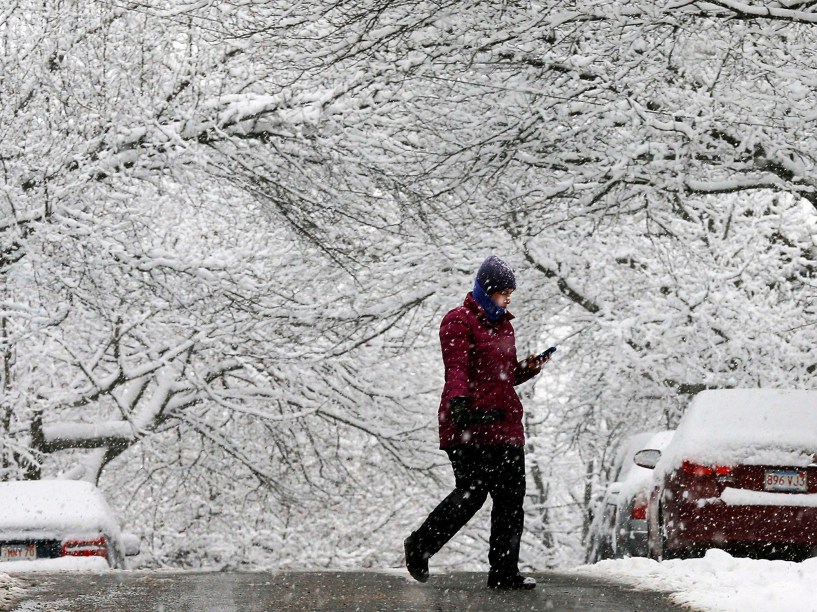 Mulher atravessa a rua debaixo de tempestade de neve em Somerville, Massachusetts