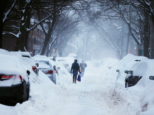 Pessoas andam por rua coberta de gelo após nevasca em Cambridge, Massachusetts