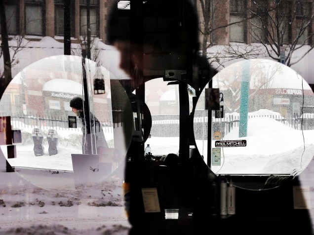Homem tem sua imagem refletida em janela e espelhos de salão de beleza durente nevasca em Brookline, Massachusetts