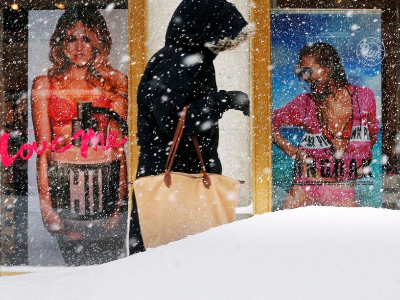 Mulher caminha debaixo de nevasca e passa em frente a loja da merca Victorias Secret em Boston