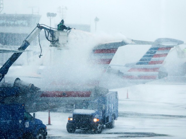 Máquina retira massa de neve de cima de avião no aeroporto de LaGuardia, em Nova York