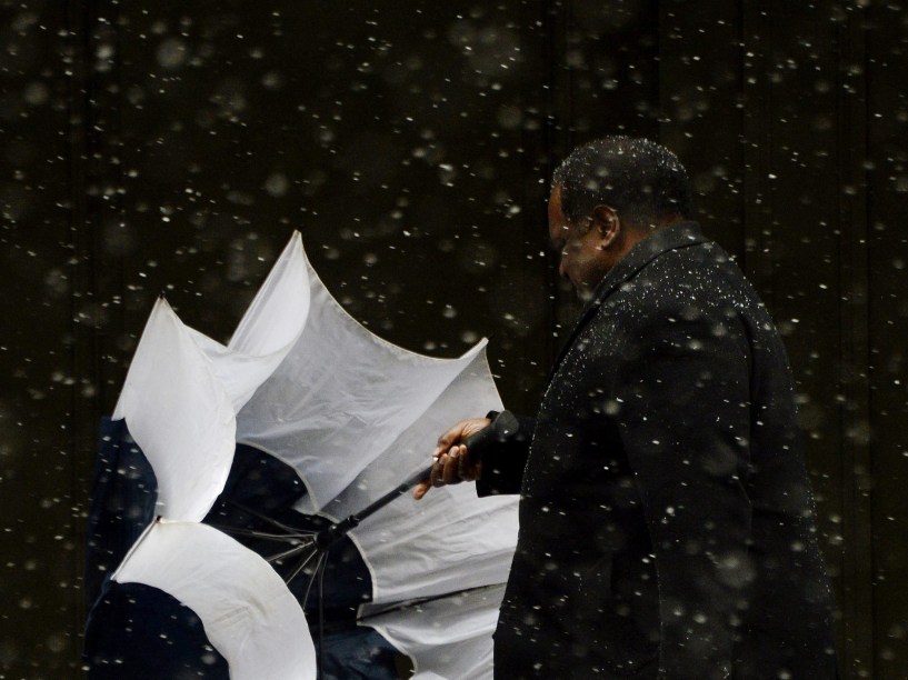 Em Nova York, homem tenta abrir sua sombrinha durante tempestade de neve que atinge o leste dos Estados Unidos