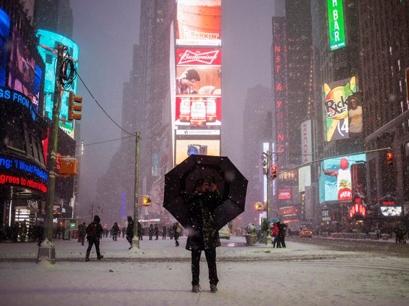 Debaixo de guarda-chuvas, homem fotografa a Times Square durante a tempestade de neve que atinge a região leste dos Estados Unidos