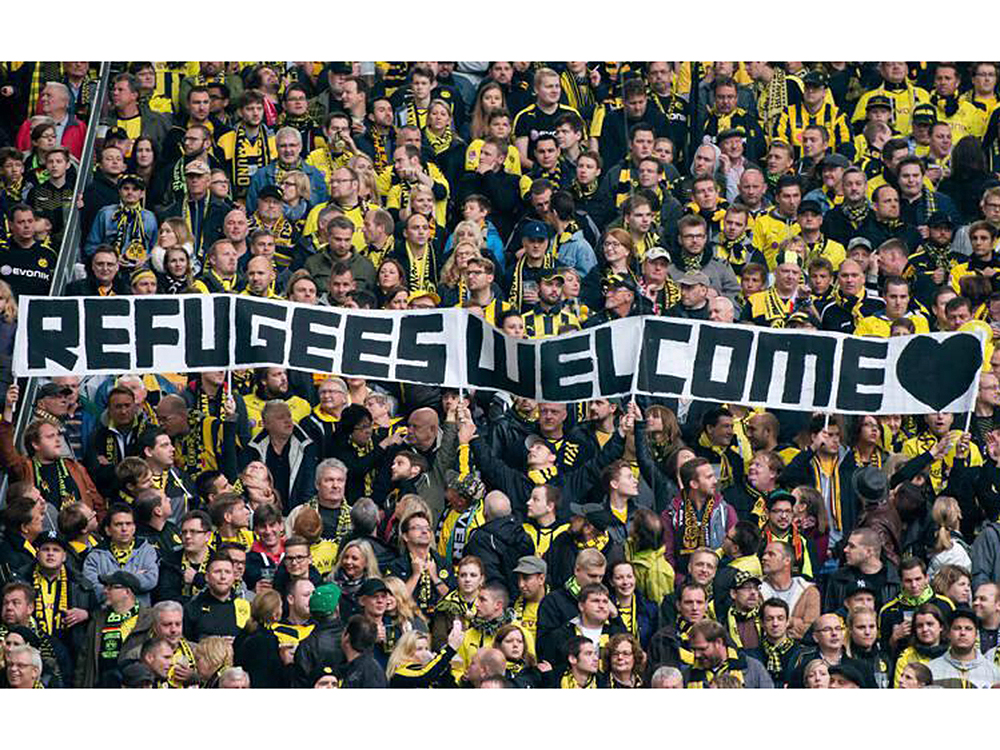 Torcida do Borussia Dortmund, da Alemanha, com faixa “Bem-vindos, refugiados”